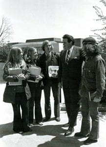 Carrier and students talking in front of Gibbons Hall. Rooted on Bluestone Hill.